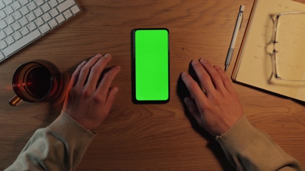男はスマートフォンの緑のモックアップ画面上で上にスワイプ — ストック動画