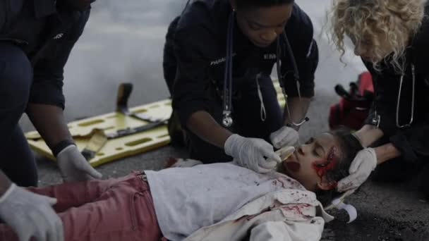 Equipage ambulancier examinant une petite fille après un accident de voiture — Video