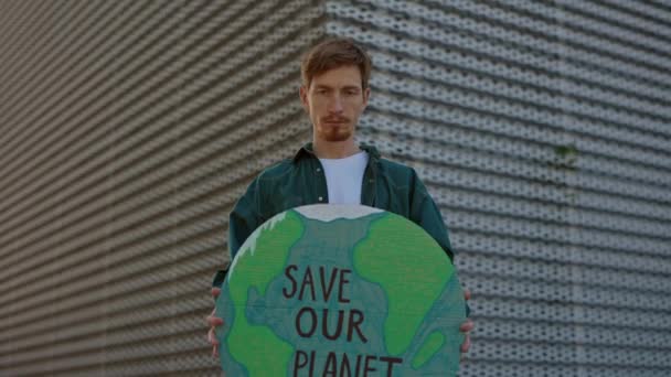 Кавказский бородатый парень держит знамя со спасением нашей планеты — стоковое видео