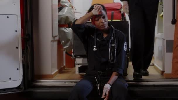 Mujer paramédica sensación de tristeza mientras está sentada en ambulancia — Vídeos de Stock