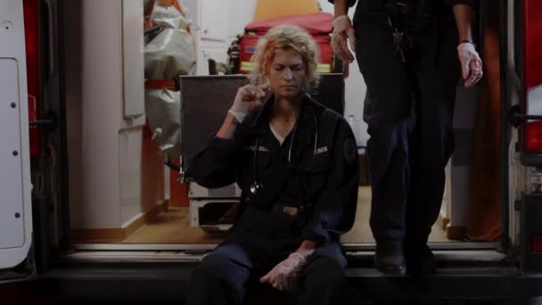 Розчарована жінка-парамедик сидить біля машини швидкої допомоги — стокове відео