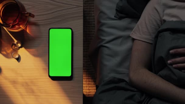 Жінка в ліжку бере зі столу мобільний з зеленим екраном — стокове відео