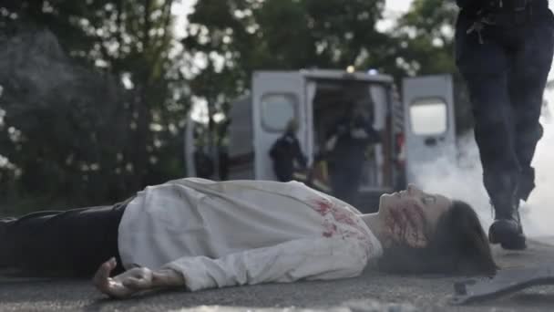 Équipe d'ambulanciers qui courent vers une femme blessée sur la route — Video