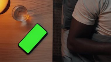 Işıkları kapatmak için yeşil ekran cep telefonuna tıklayan adam
