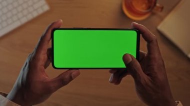 Siyah erkek ellerinde yeşil ekran olan akıllı telefon.