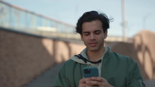 Cheerful man using smartphone while walking on street — Stock Video