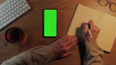 Yapılacak işleri yazan ve boş ekranlı cep telefonu kullanan adam