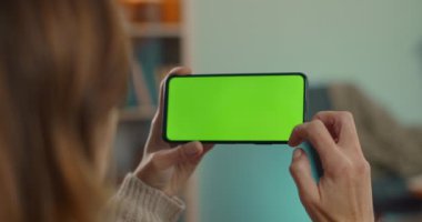 Akıllı telefon tutan ve yeşil ekrana vuran kadın.