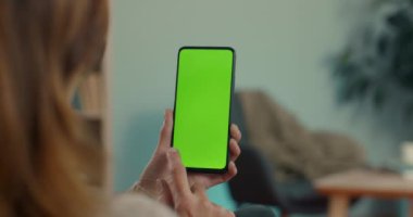 Akıllı telefon tutan ve yeşil ekranda kayan kadın