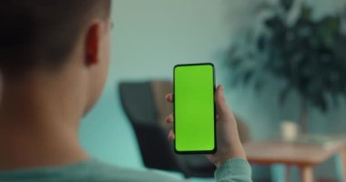 Elinde akıllı telefon tutan adam yeşil ekranı taklit ediyor.