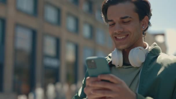 Мужчина пользуется мобильным телефоном во время прогулки по улице — стоковое видео