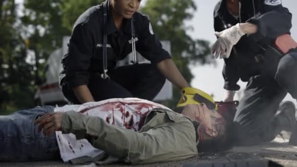 Les travailleurs médicaux courent à l'homme blessé qui se trouve sur la route — Video