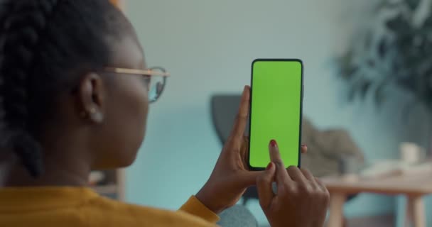 Afrika kökenli Amerikalı bir kadın yeşil ışıkta geçiyor. Mobil ekran modeli yapıyor. — Stok video