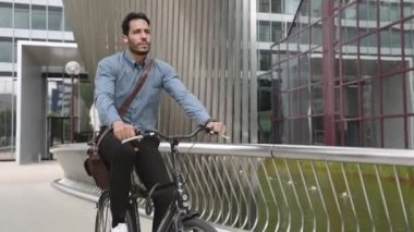 Kulaklık takan iş adamı bisikletle ofise gidiyor.
