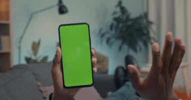 Afrika kökenli Amerikalı bir adam yeşil ekranlı cep telefonu kullanıyor.