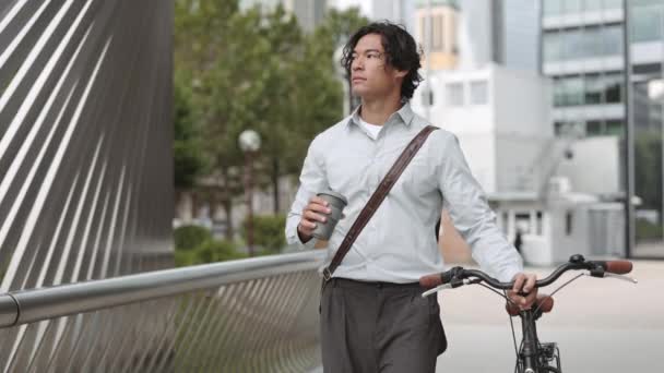 Hombre de negocios asiático caminando con bicicleta y taza de café — Vídeos de Stock