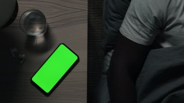 Adam ışıkları açıyor ve yeşil mobil ekrana vuruyor.