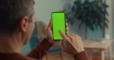Video çağrısı için yeşil ekranlı cep telefonu kullanan beyaz bir adam.