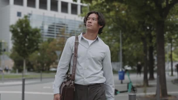 スーツケースを着たアジア人ビジネスマンが街を歩く — ストック動画