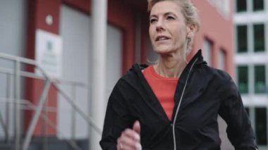 Kentsel alanda spor kıyafetleri içinde koşan son sınıf öğrencisi bir kadın.