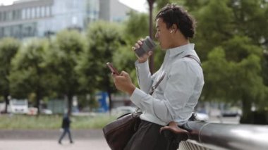 Kulaklık takan ve kahve içen bir iş adamı.