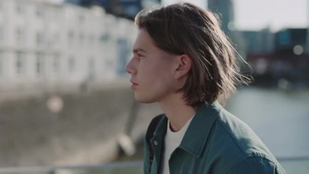 Snygg kille med trendig frisyr tittar på kameran utomhus — Stockvideo