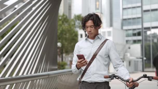 Asiatique homme marche sur la rue avec vélo et smartphone — Video