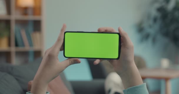 Man met smartphone met groene mock-up scherm thuis — Stockvideo