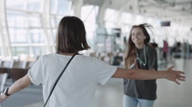 Havaalanında buluşurken kucaklaşan iki lezbiyen.