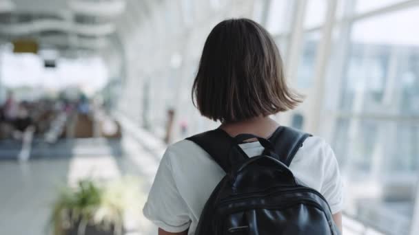 Mulher com mochila andando no aeroporto — Vídeo de Stock