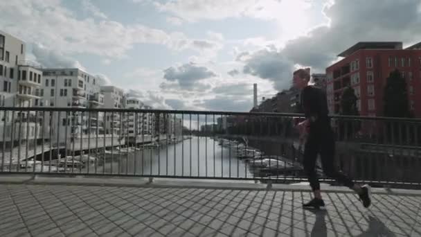 Donna in età attiva che corre lungo il ponte sul fiume della città — Video Stock