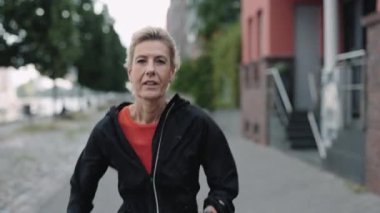 Spor elbiseli aktif bir kadın sokakta tek başına koşuyor.