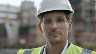 Dışarıda duran kasklı, kendinden emin bir erkek müteahhit.