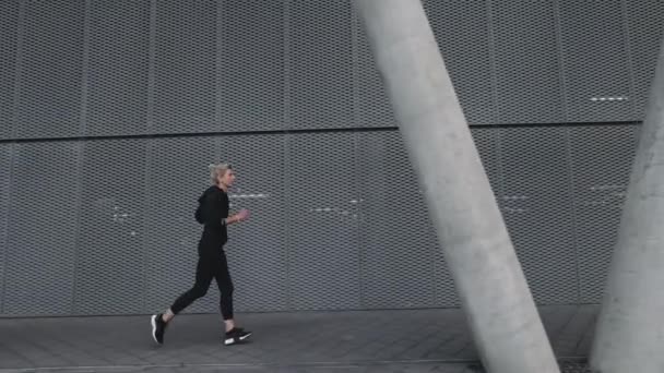 Volwassen vrouw in sport kleding joggen op stad straat — Stockvideo