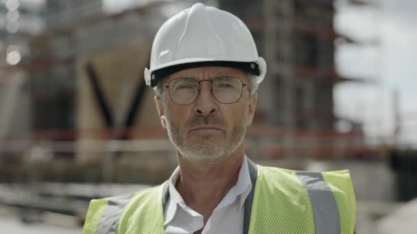 Man in hardhat standing outdoors and looking at camera — Stock Video