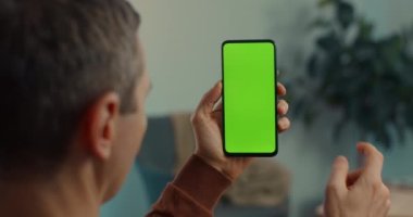 Olgun adam akıllı telefonun yeşil boş ekranını tıklatıyor