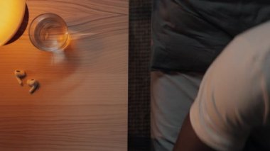 Zenci adam uyurken cep telefonunu masaya koyuyor.