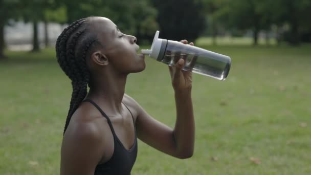 Woman drinking water after intense workout outdoors — Stockvideo