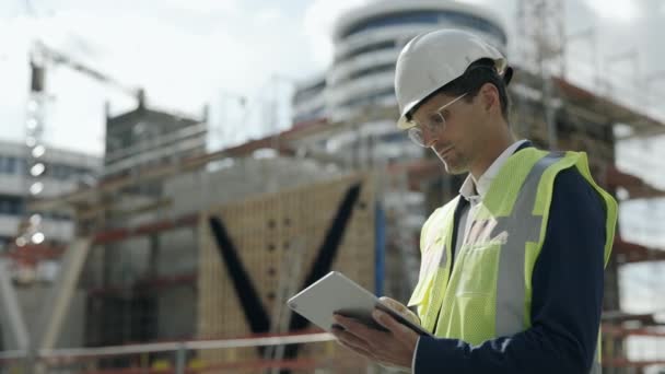 Architekt w kasku korzystający z tabletu na placu budowy — Wideo stockowe