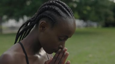 Afro-Amerikalı kadın dışarıda meditasyon yapıyor.