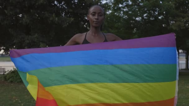 Afro-Amerikaanse vrouw in sportkleding met regenboog vlag — Stockvideo