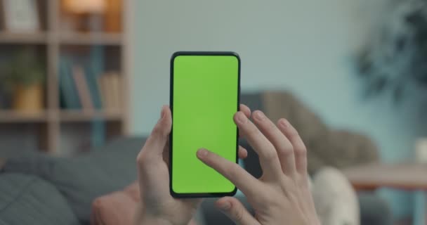 Close-up van de mens met behulp van mobiele telefoon met groen scherm thuis — Stockvideo