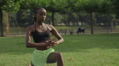 Dışarıda yoga minderi üzerinde esnek egzersizler yapan bir kadın.
