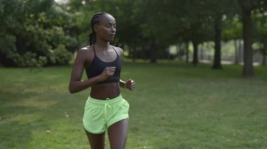 Spor elbiseli atletik kadın parkta koşuyor.