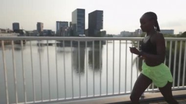 Aktif giyimli Afrikalı Amerikalı kadın köprüde hızlı koşuyor.