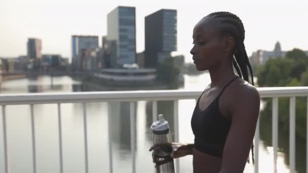 Жінка бігунка використовує розумний годинник і несе пляшку води — стокове відео