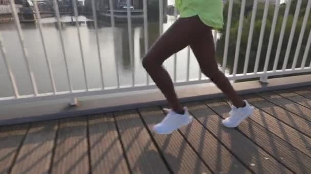 Närbild av afrikansk amerikansk kvinna joggar längs bron — Stockvideo