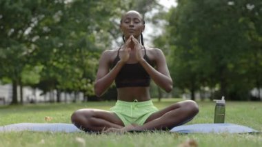 Afrikalı Amerikalı kadın yeşil park arasında meditasyon yapıyor.