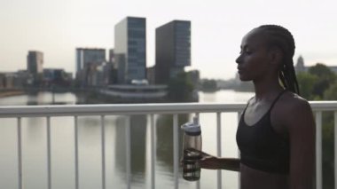 Açık hava koşusundan sonra su içen Afrikalı Amerikalı kadın.