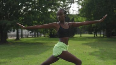 Afrikalı Amerikalı kadın parkta yoga egzersizi yapıyor.